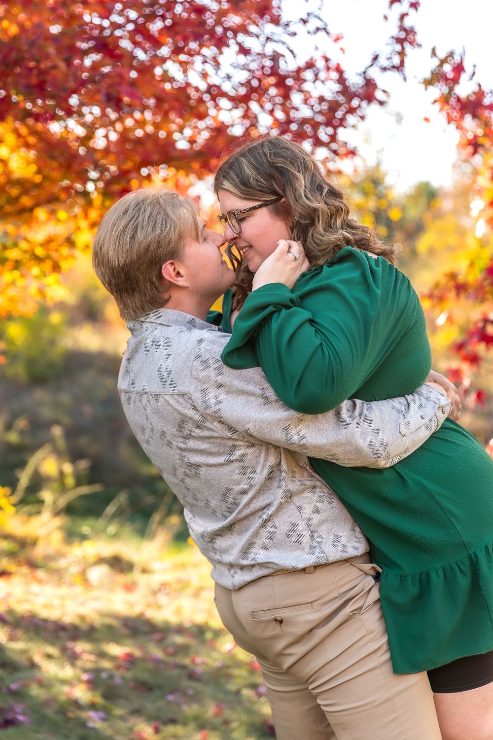 A romantic couple shares an intimate moment against bright fall foliage.