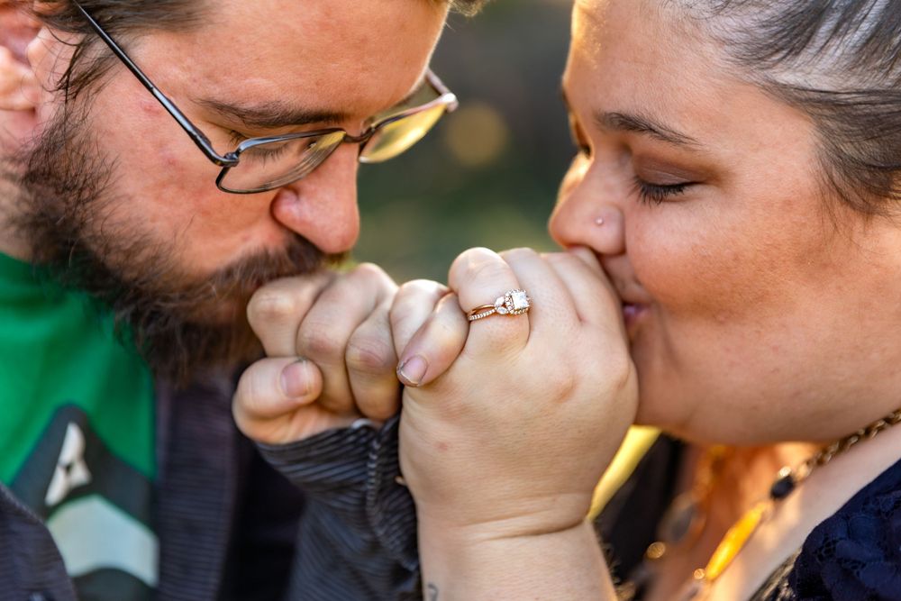 A close up of hands and rings as a couple shares an intimate moment.