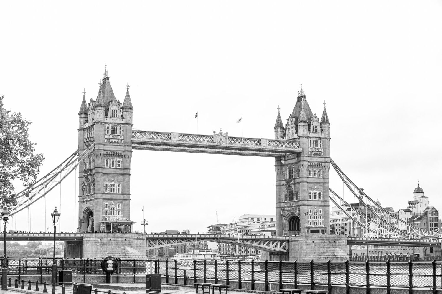 Historic Tower Bridge in London captured in black and white with its iconic twin towers and suspended walkway.