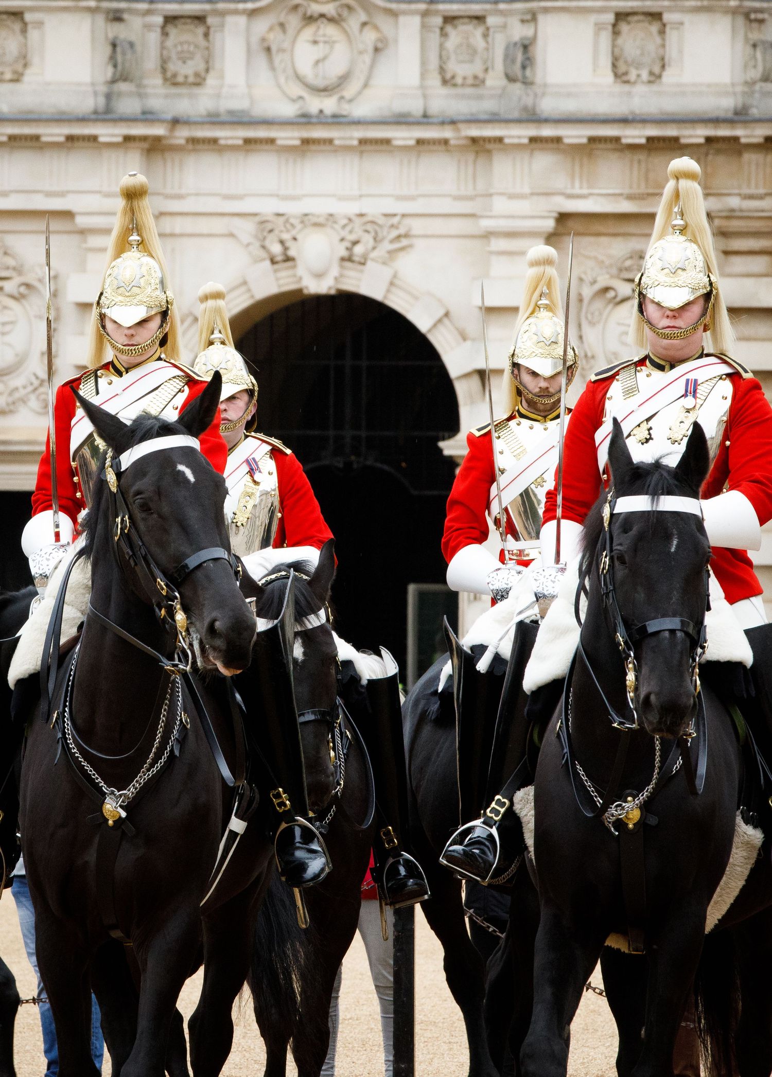 Four mounted members of the Queens Household Cavalry in ceremonial uniforms on black horses at Horse Guards Parade in London.