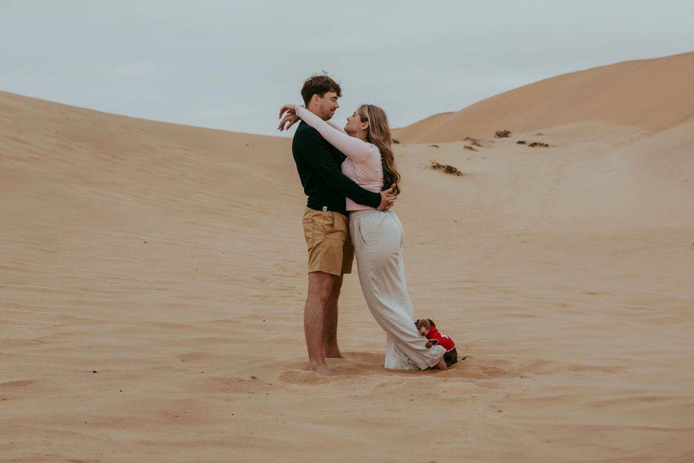 A couple with their dog in the Namib Desert dunes, surrounded by golden sand and vast open skies, capturing a moment of adventure