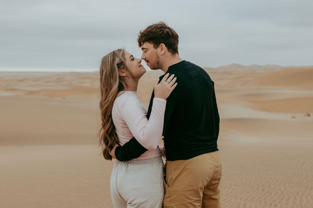 A couple with their dog in the Namib Desert dunes, surrounded by golden sand and vast open skies, capturing a moment of adventure