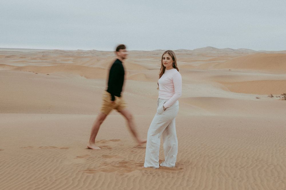 A couple with their dog in the Namib Desert dunes, surrounded by golden sand and vast open skies, capturing a moment of adventure
