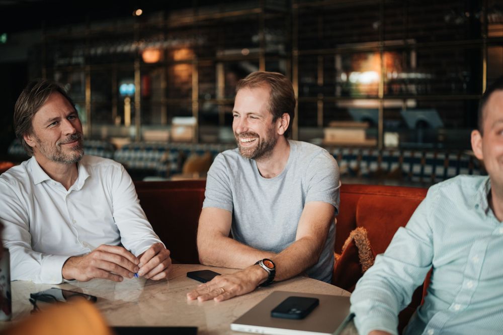 Three friends enjoying casual conversation and drinks together at a cozy pub or restaurant.