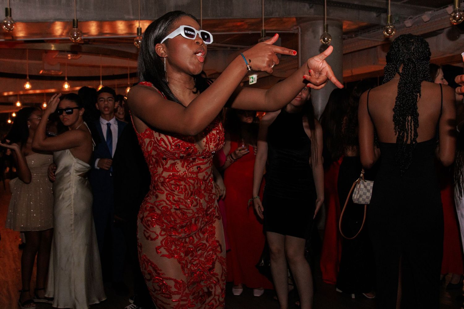 Festive party scene with red ambient lighting and dancing guests in formal wear.