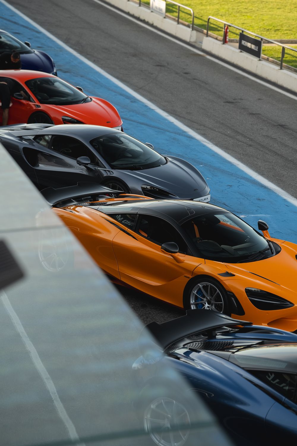 Row of luxury McLaren supercars lined up in the paddock — Richard Mille brand event photography — Paul Brechu