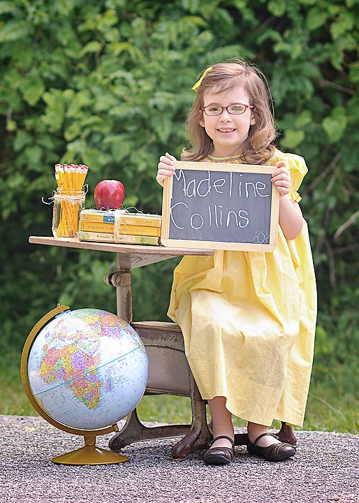 kindergarten graduate sitting at a desk holding a chalkboard