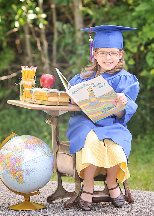 kindergarten graduate outside sitting at a desk holding where you will go book