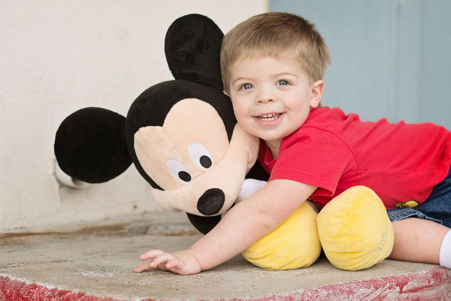 toddler smiling with mickey mouse stuffed animal