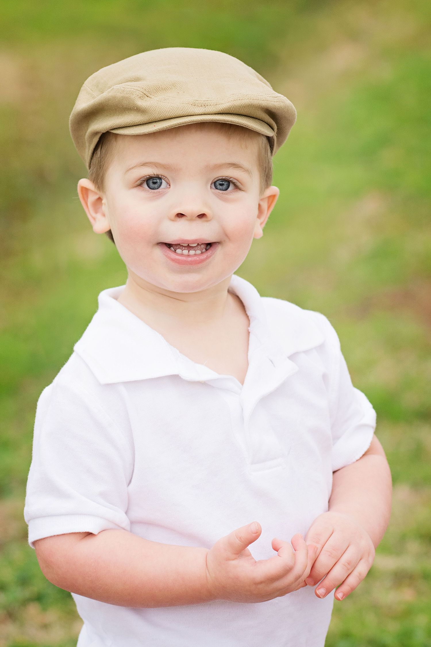 smiling toddler wearing newsboy cap outside
