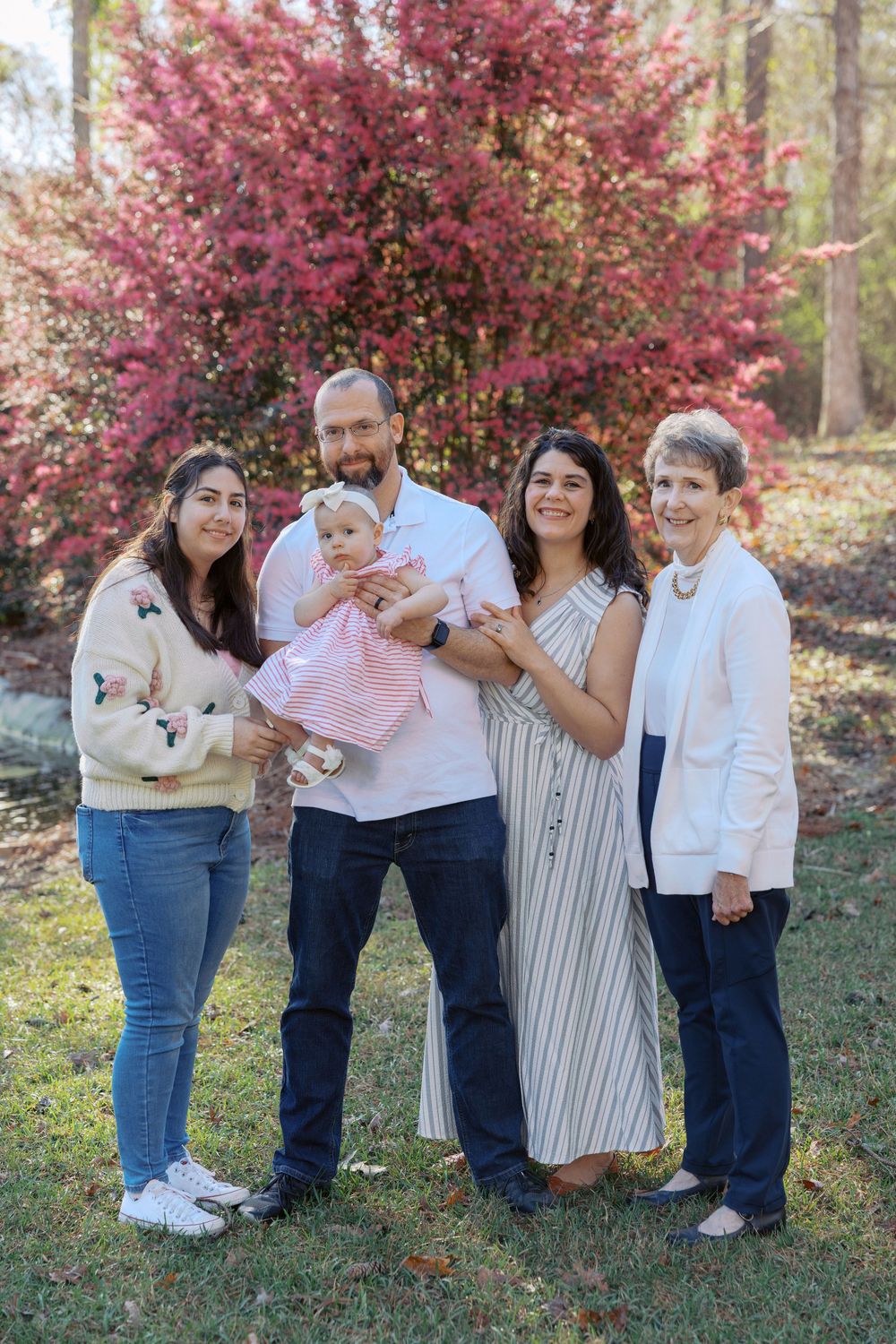 Group poses together outdoors in front of a blooming pink flowering tree on an autumn day.