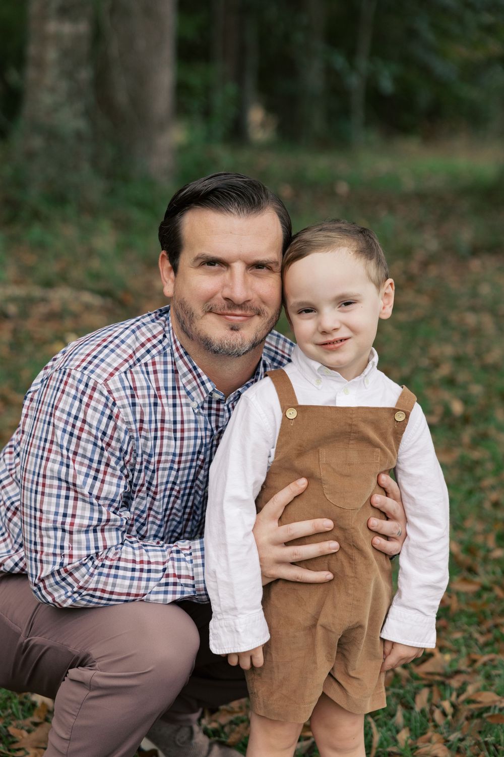 Outdoors fall portrait of parent and child in coordinating outfits with brown corduroy overalls and plaid shirt.