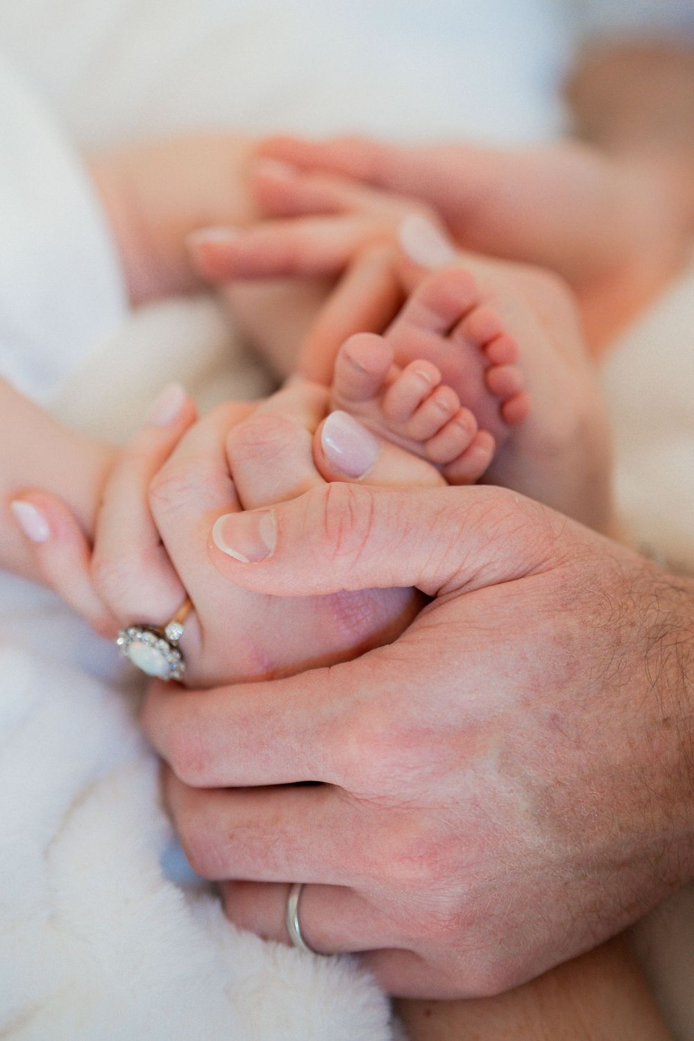Newborn's tiny feet cradled in parents' hands