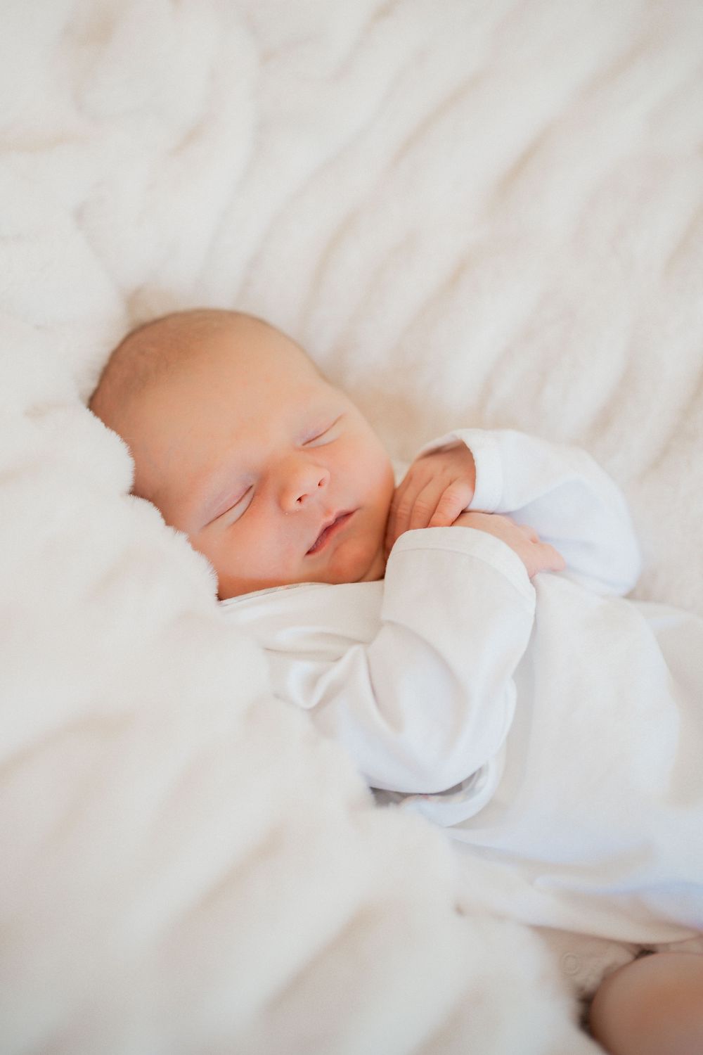 Newborn baby swaddled in a cream wrap during an in-home lifestyle session