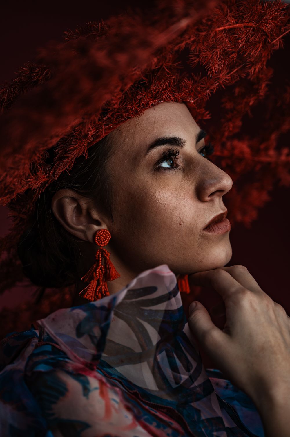 Dramatic portrait with red earrings and floral print against dark red background. SIX84 Photography, Portrait Photography, Sydney