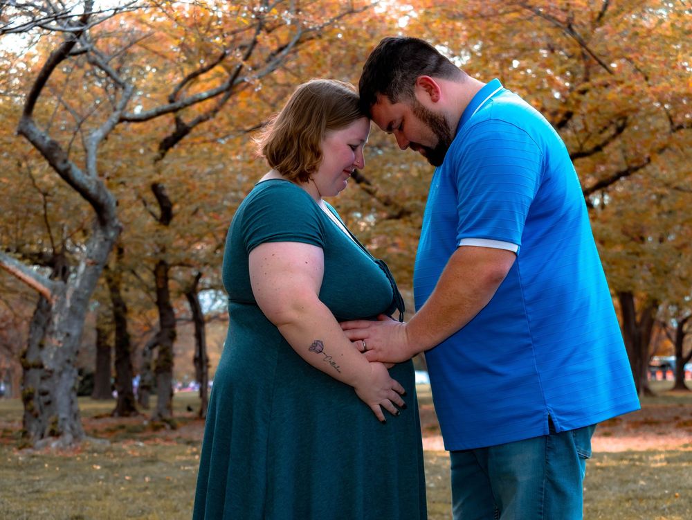 Romantic couple sharing a tender moment in a park with beautiful fall foliage and golden autumn trees in background.