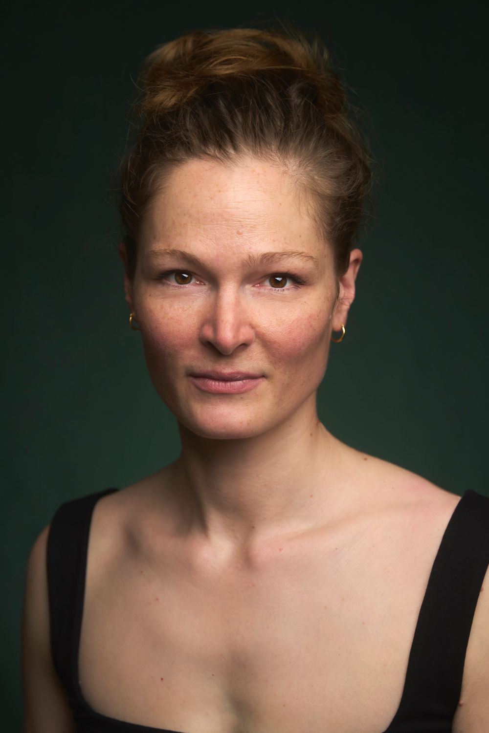 Portrait artistique en studio sur fond vert foncé avec un éclairage spectaculaire.