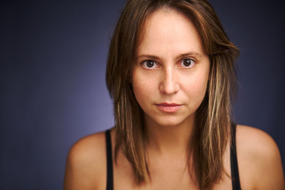 Portrait en studio sur fond bleu foncé dans un éclairage naturel.