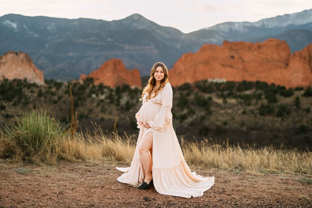 A panoramic view of Garden of the Gods park in Colorado Springs with red rock formations and mountain backdrop for woman's maternity photos.