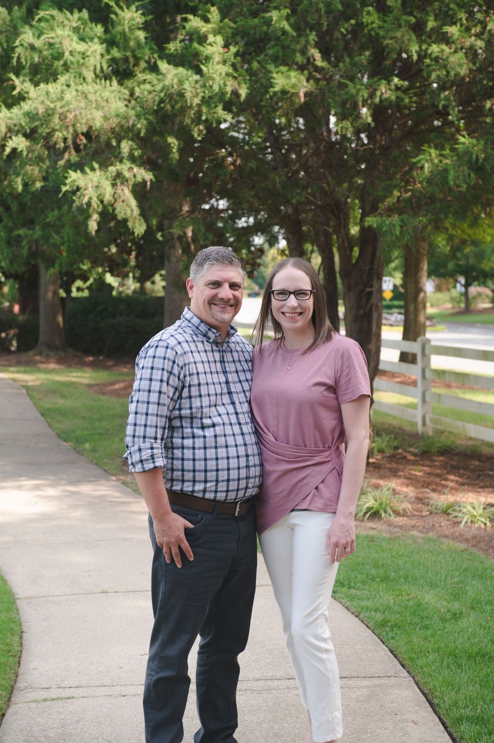 Casual outdoor portrait session on a sidewalk with landscaped grounds in background.