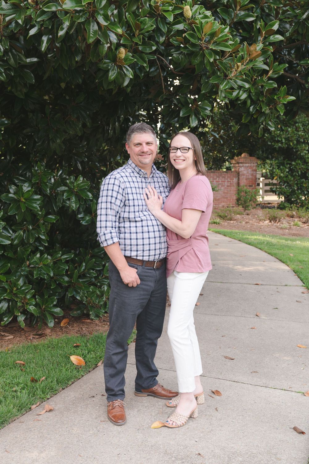 Cheerful outdoor portrait session along a garden path with magnolia trees.