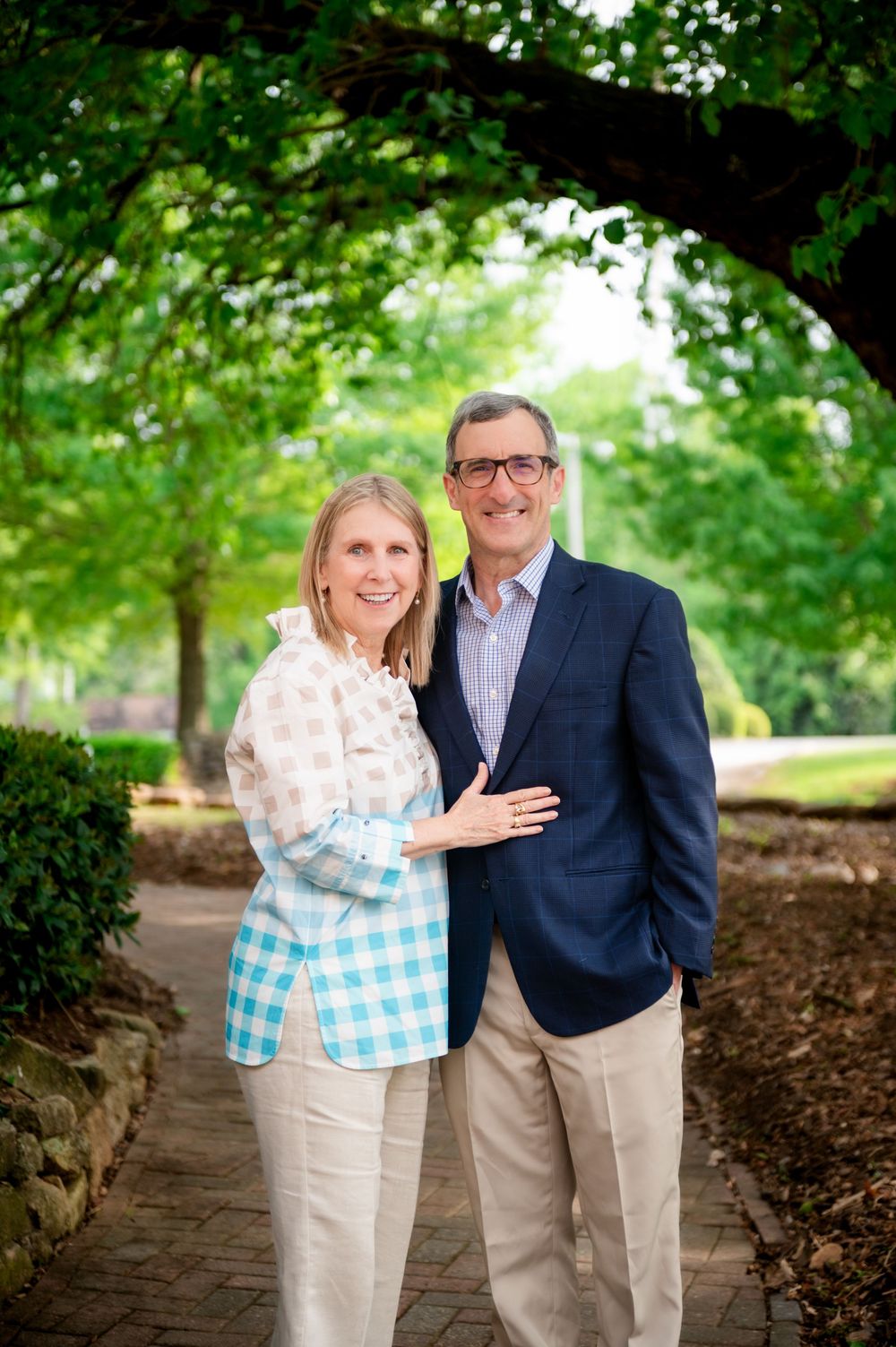 Romantic outdoor portrait session under green tree canopy with natural lighting.