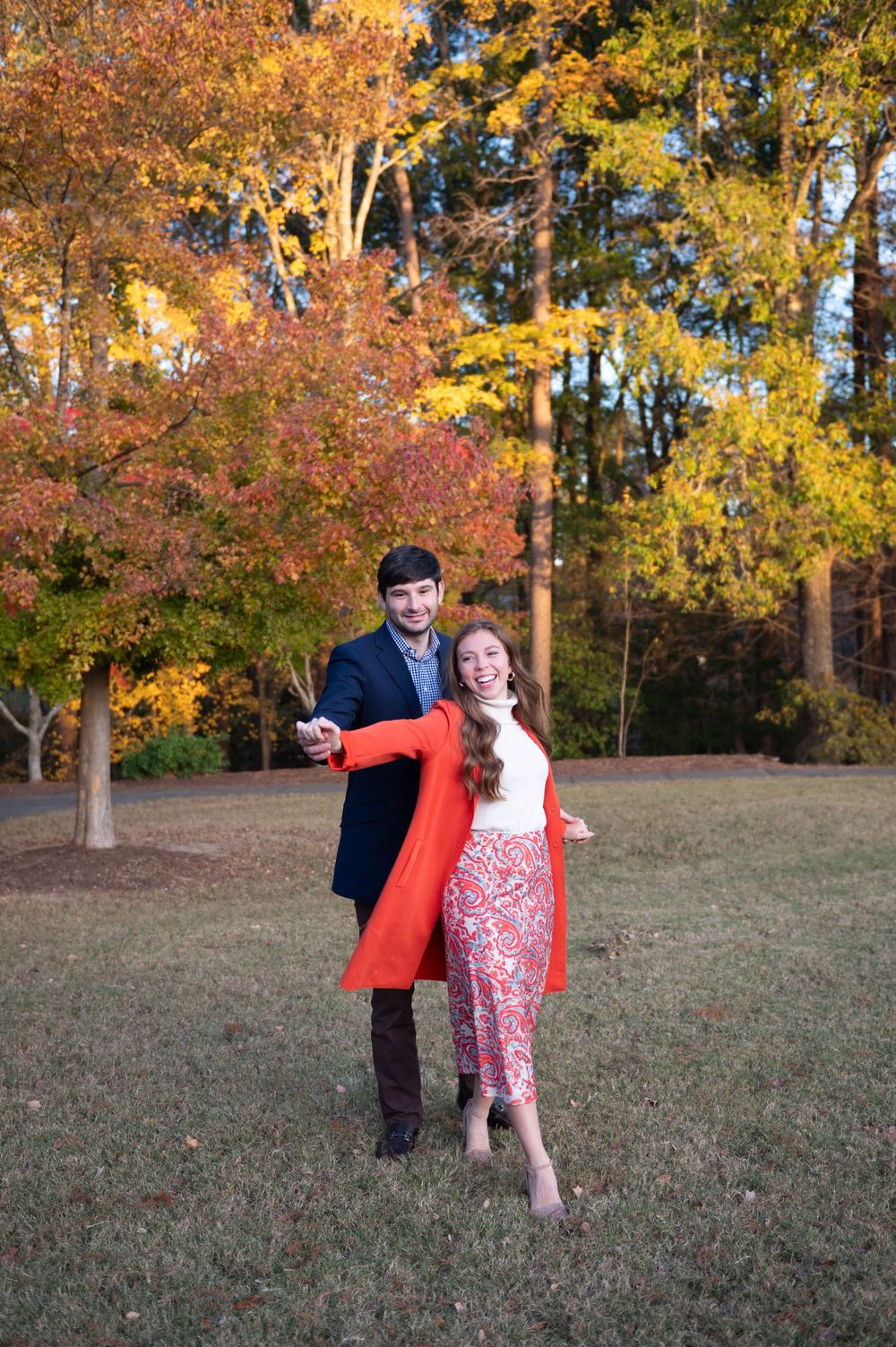 Playful autumn engagement session with dancing and spinning in a park.