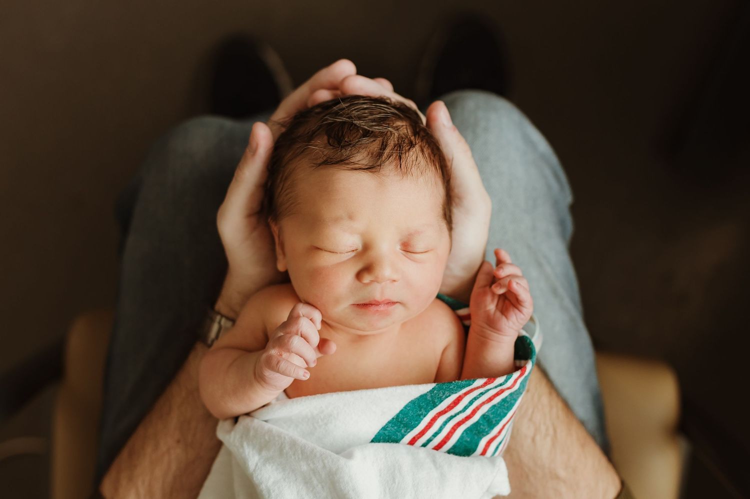 A newborn baby cradled in dads hands