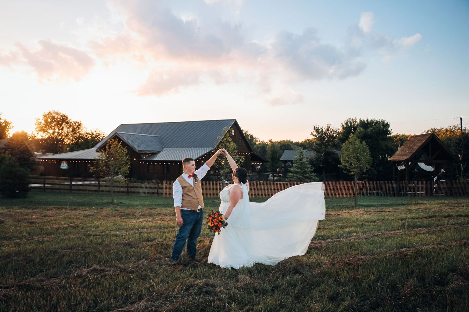 Wedding couple in rustic field setting during golden hour with flowing veil. wedding photography