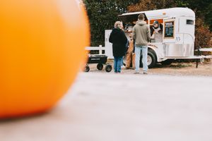 pumpkin in the foreground and mobile ice cream trailer in the back ground serving customers