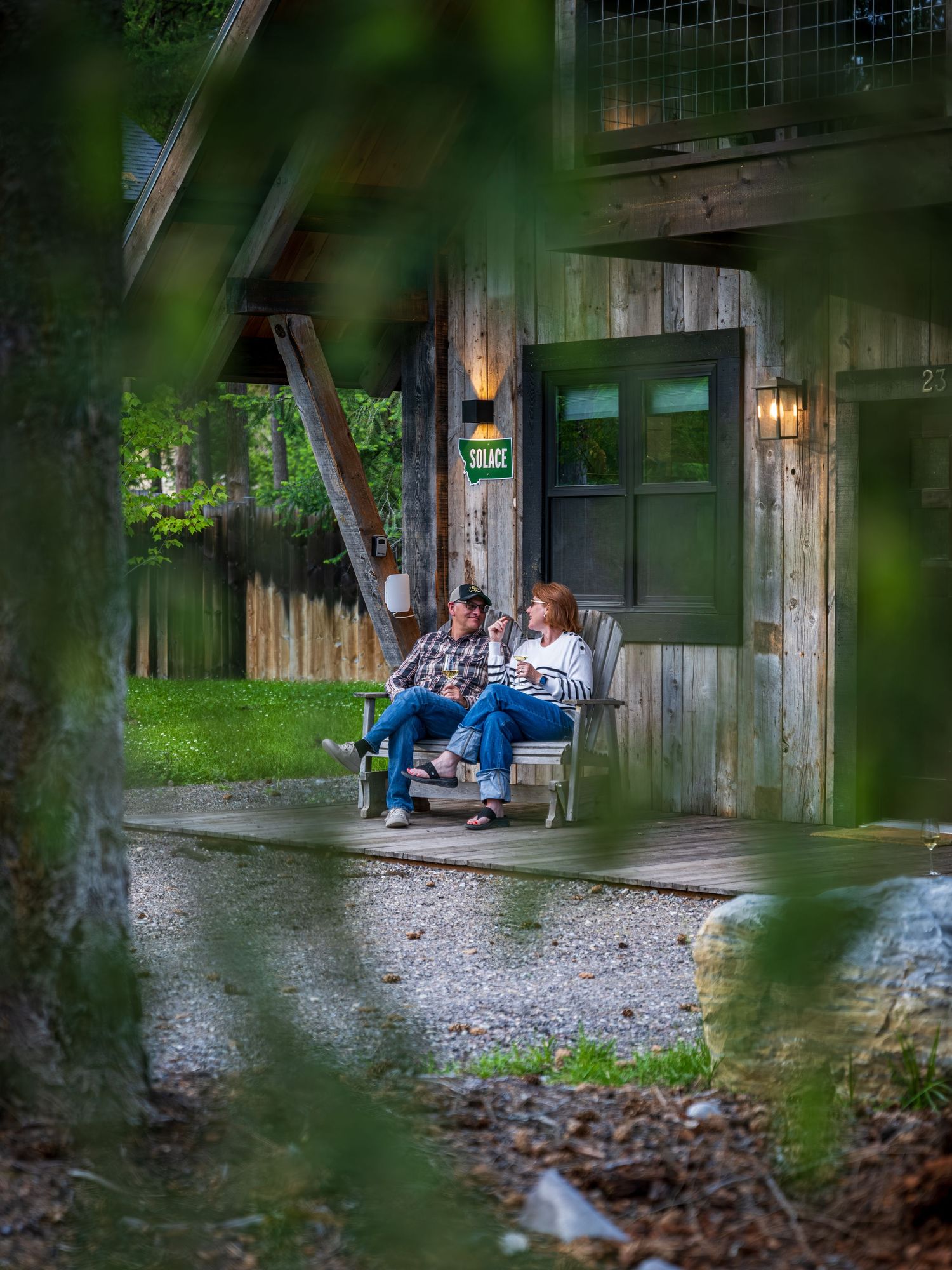 A couple sitting & relaxing on the front porch of a luxury vacation rental in Whitefish, MT.