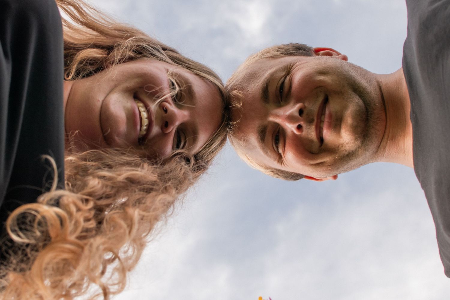 A couple relaxes together on a blanket in a sunny meadow.