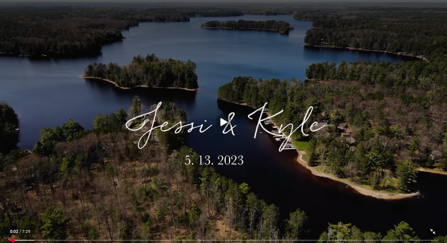 Aerial view of Jessi and Kyle's wedding date May 13, 2023, overlooking a serene lake surrounded by lush forest.