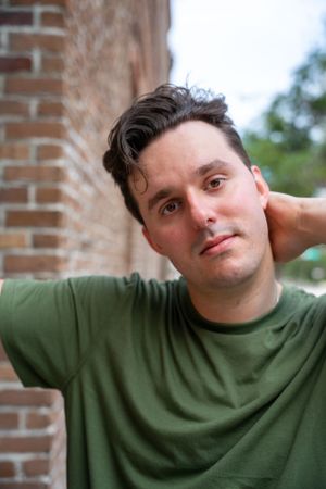 Casual outdoor portrait against brick wall background in natural lighting.