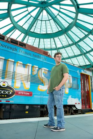 Indoor portrait under teal dome ceiling with vintage trains in background.