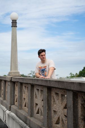 Figure resting on concrete wall with decorative architectural details and blue sky.