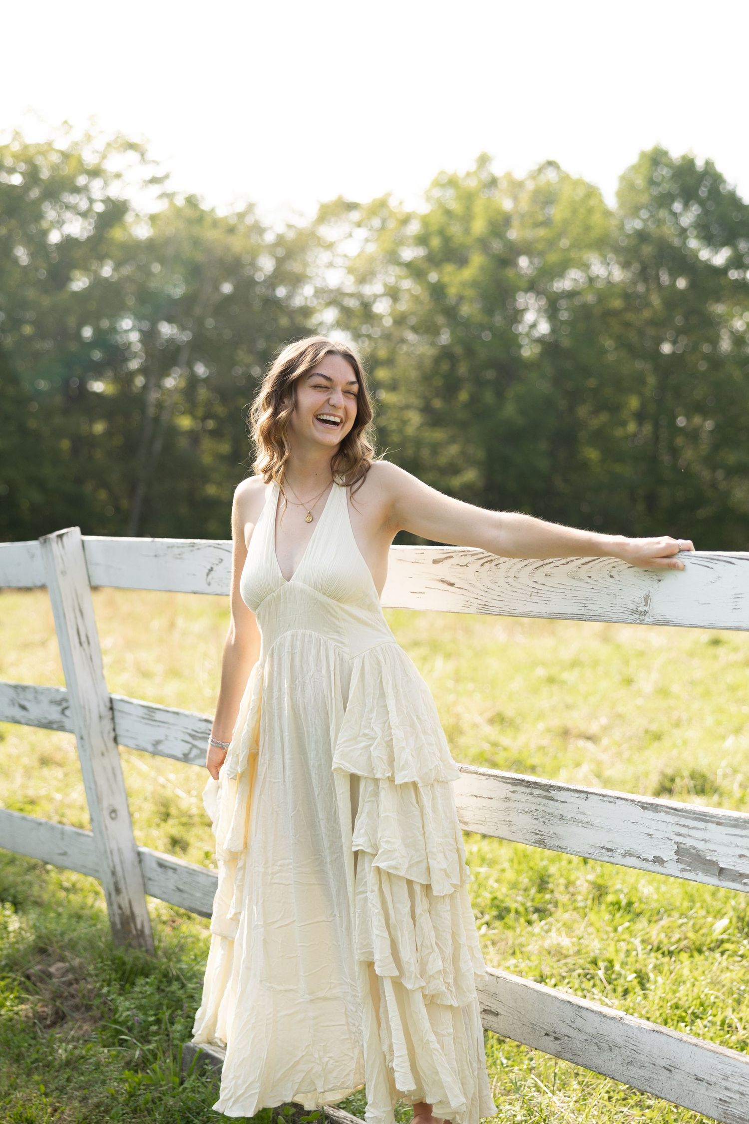 Young woman in green sundress sitting on grass holding wildflower bouquet outdoors.