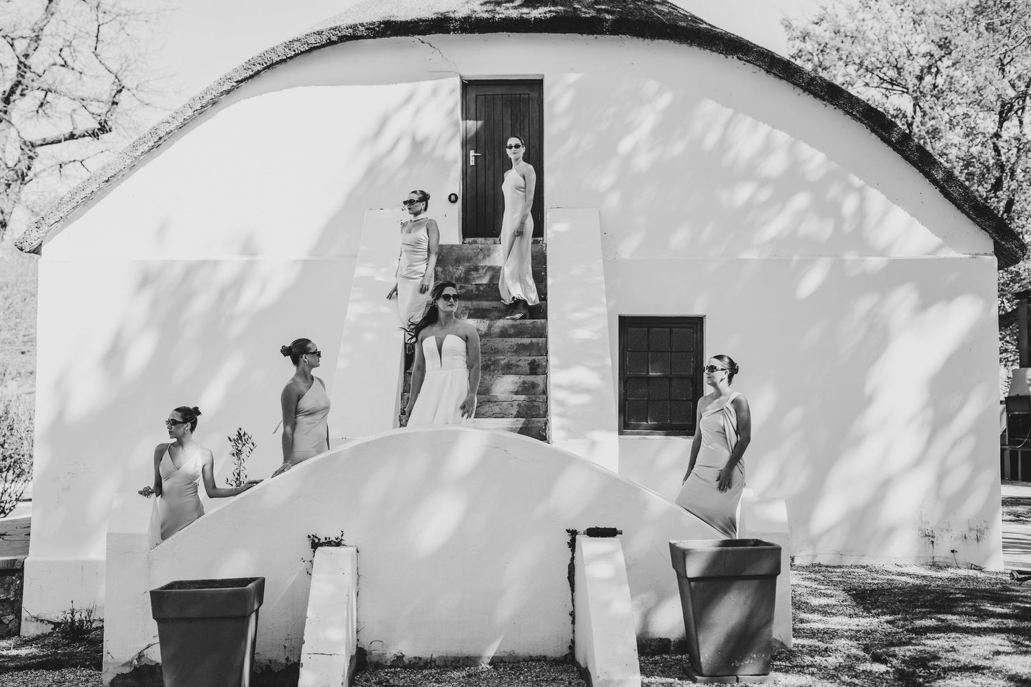 A black and white photo series shows the progression of a person walking past a white wall with shadows cast by trees.