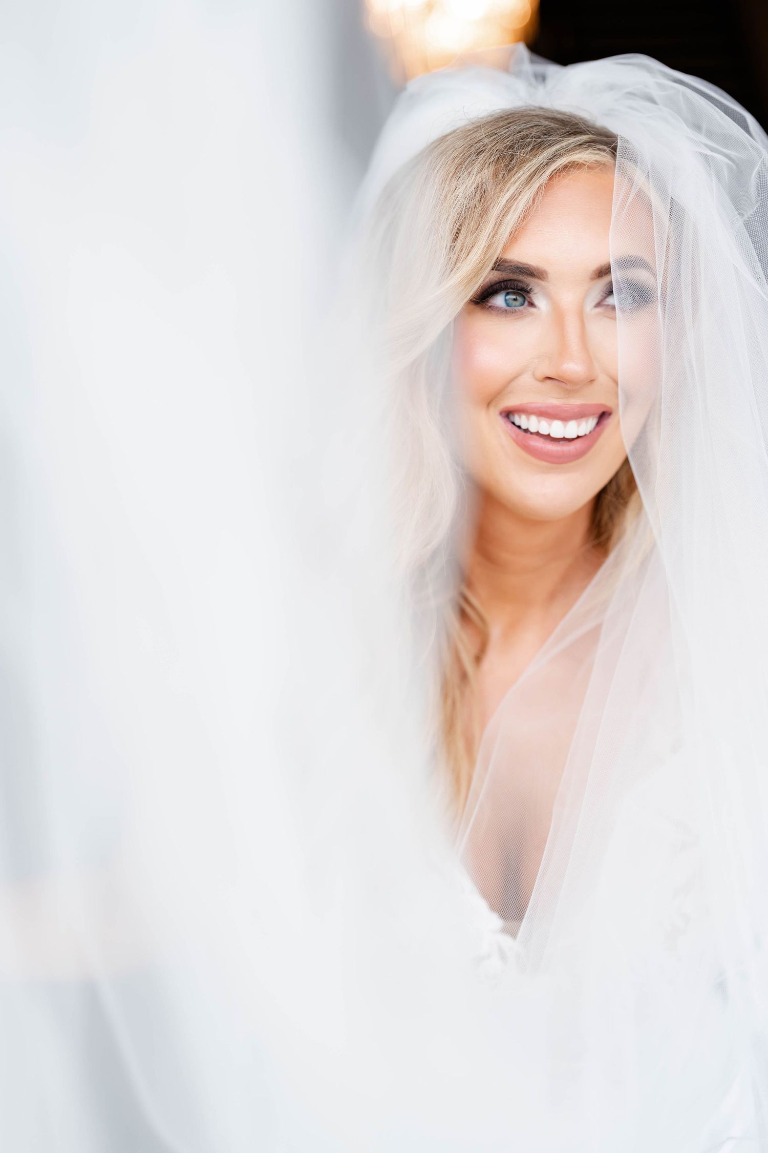 Ethereal bridal portrait with soft lighting through white veil.