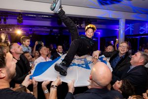 Bar Mitzvah boy is thrown in the air from an Israeli flag at a party - Bar Mitzvah Photography