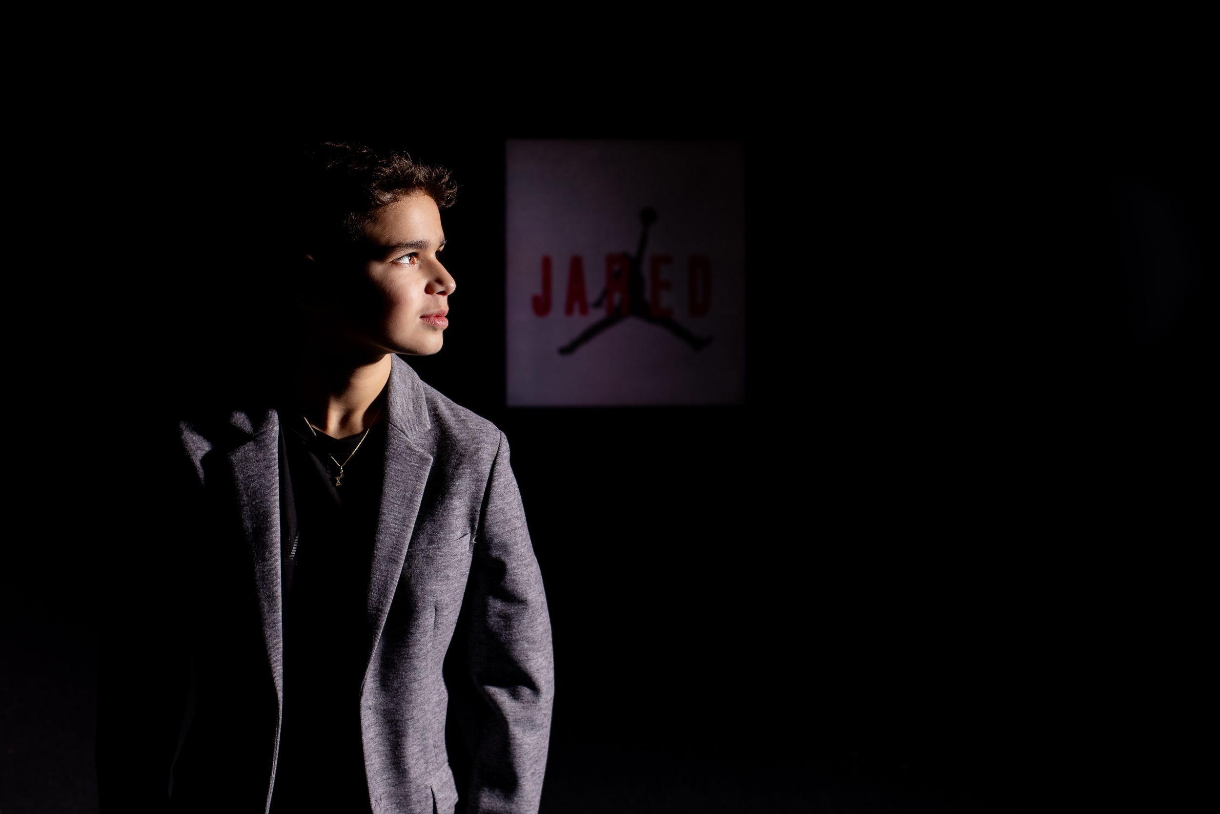 Bar Mitzvah boy poses in front black wall - Bar Mitzvah Photography