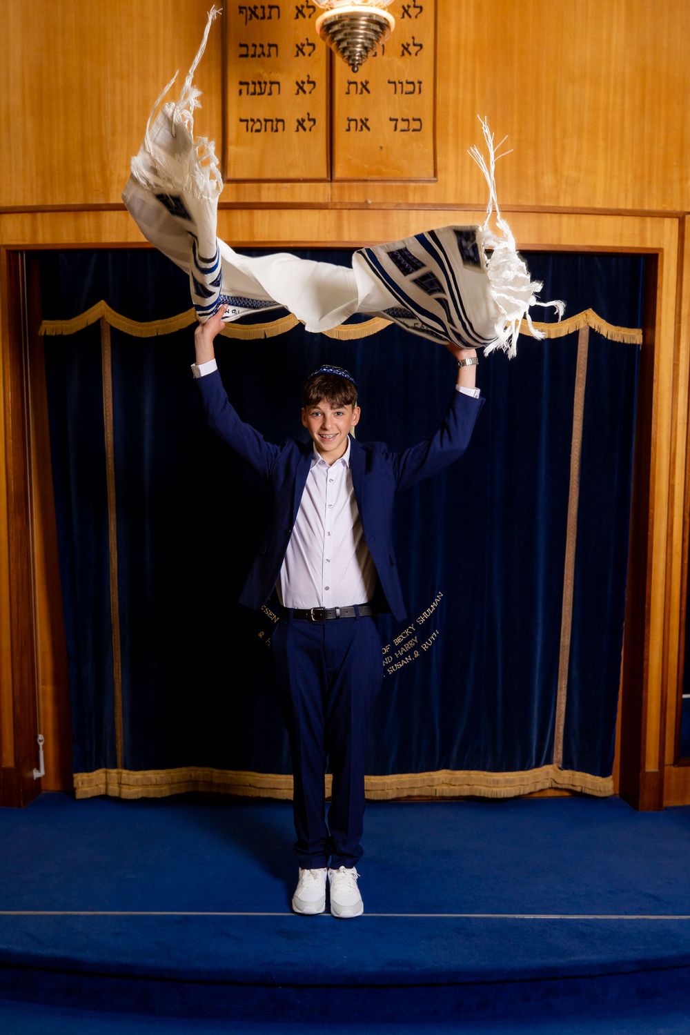 Bar Mitzvah boy throws his tallis in the air in front of the ark - Bar Mitzvah Photography