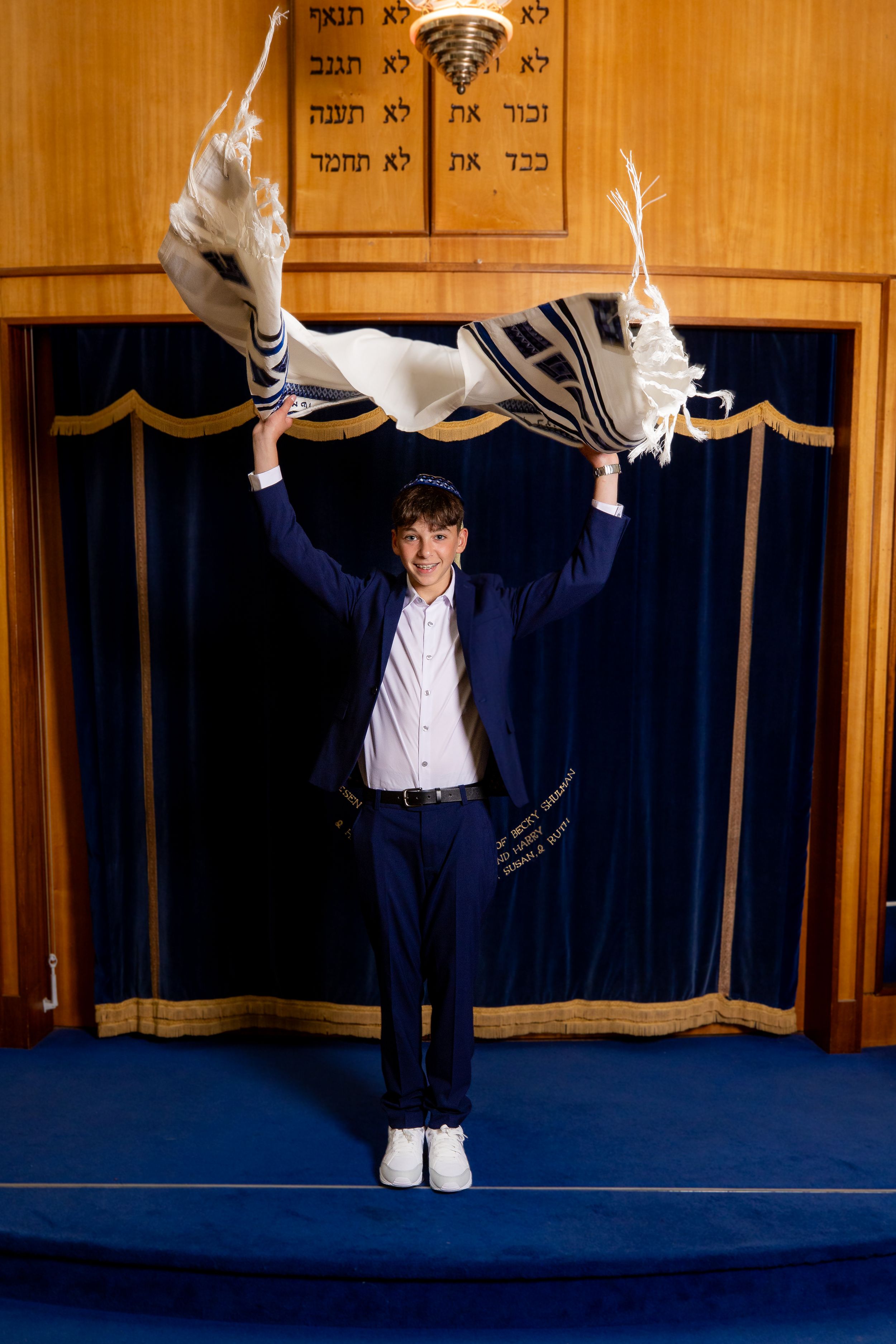 Bar Mitzvah boy throws his tallis in the air in front of the ark - Bar Mitzvah Photography