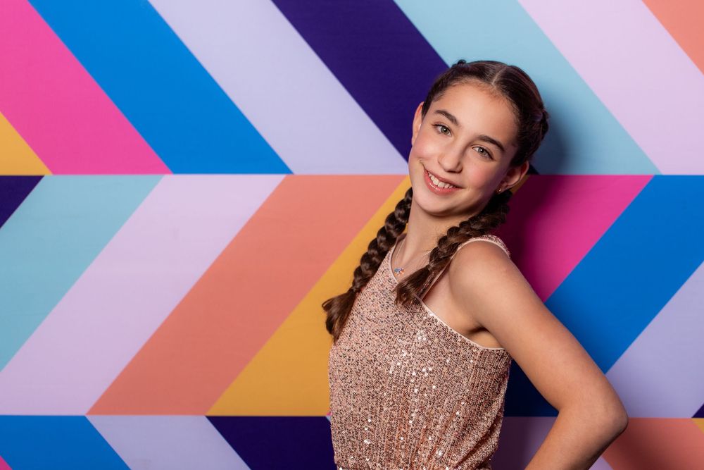 Bat Mitzvah girl poses against a colourful wall - Bat Mitzvah Photography