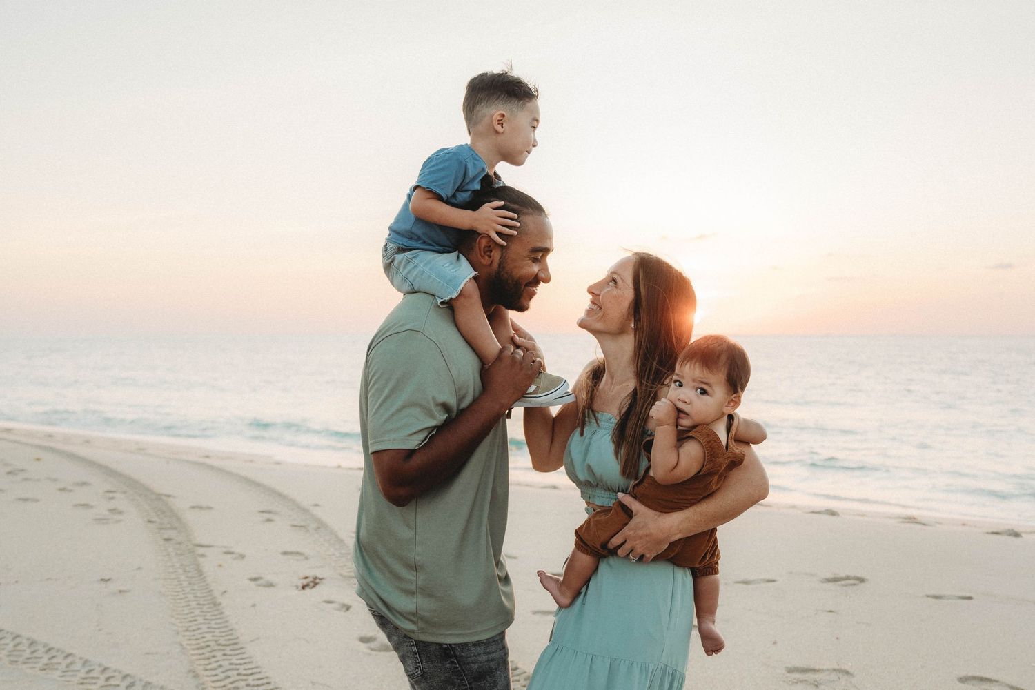 Happy Palm Beach family enjoying sunset moment together on beach with ocean backdrop.