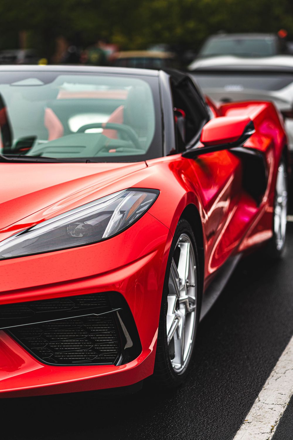 Sleek red Corvette C8 with aggressive styling and sharp body lines parked on street.