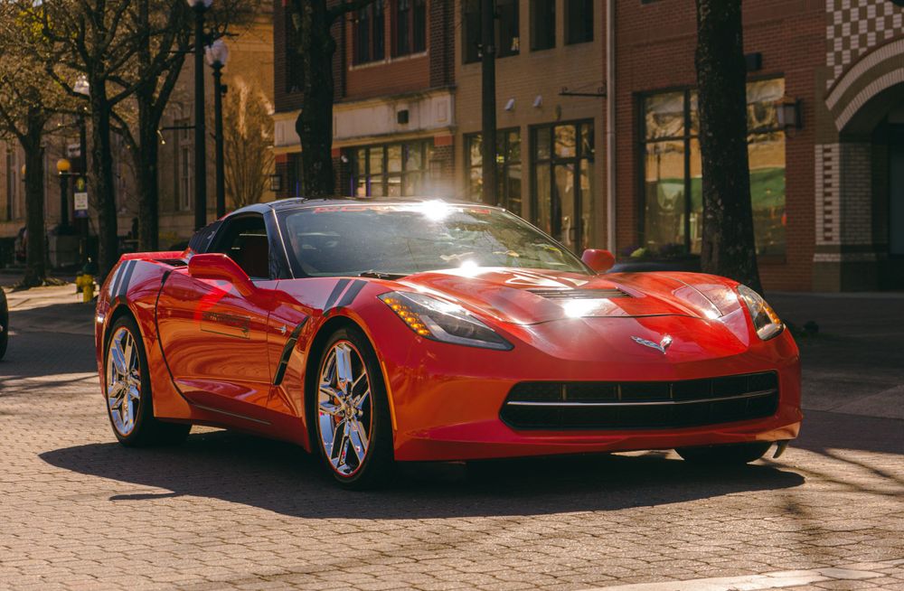 Red Chevrolet Corvette parked on a brick-paved street at dusk.