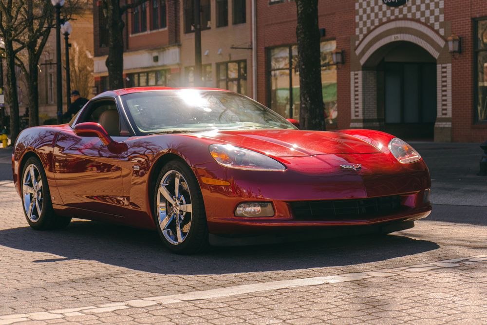 Red C6 Corvette displaying its classic sports car styling on a brick street.