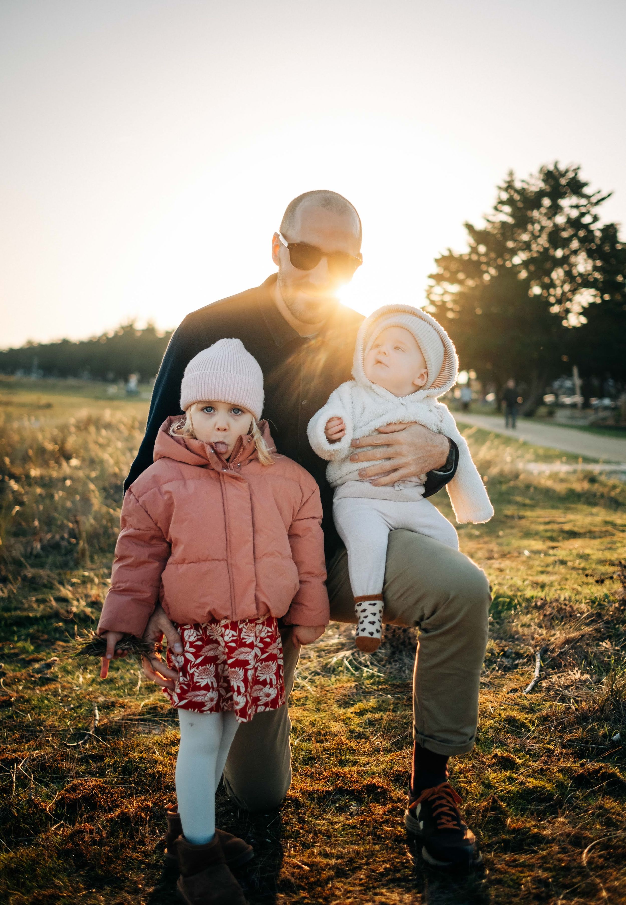 Sunset family moment captured with children in winter coats during golden hour.