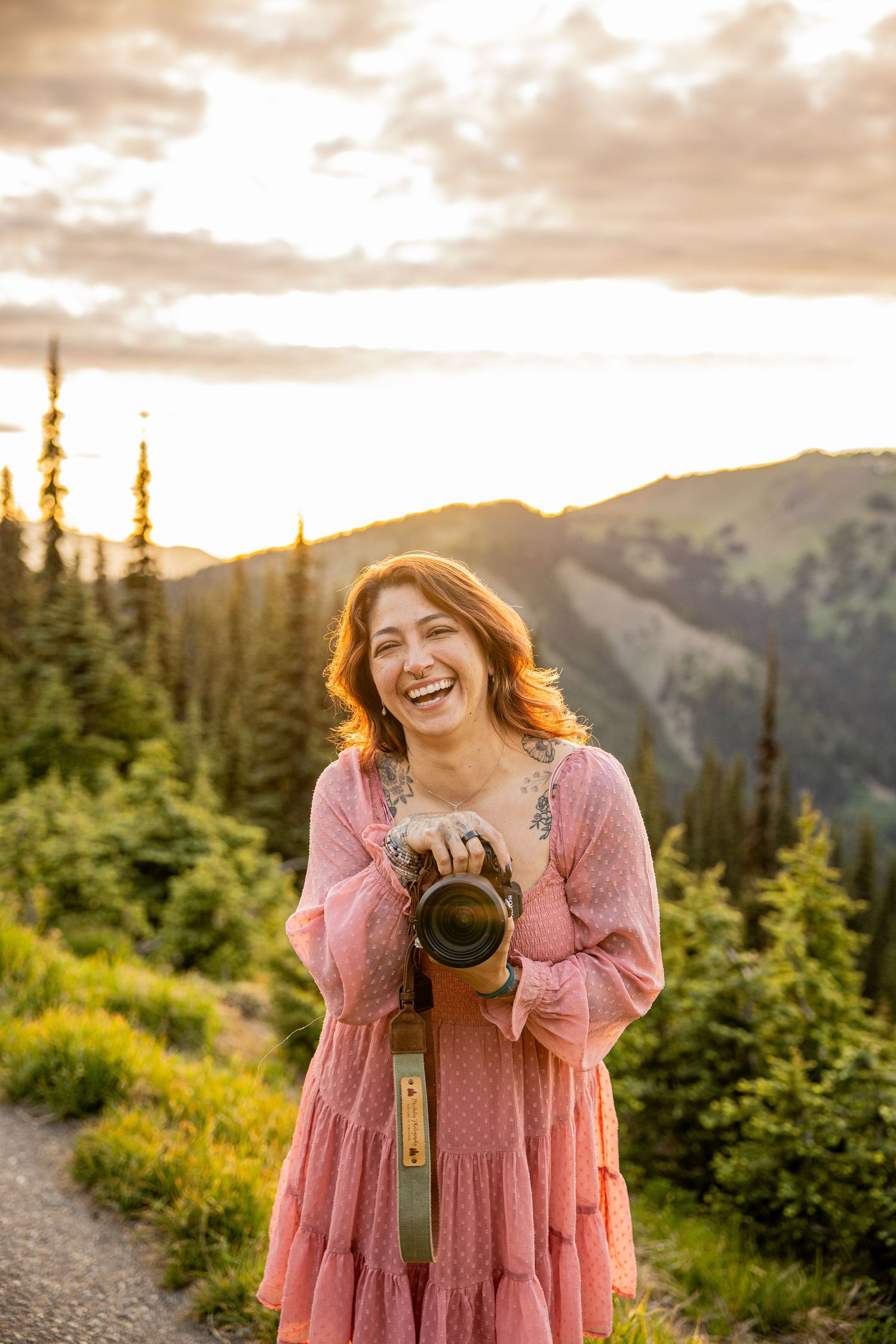 Person in yellow sweater and ripped jeans holding camera poses against white background.